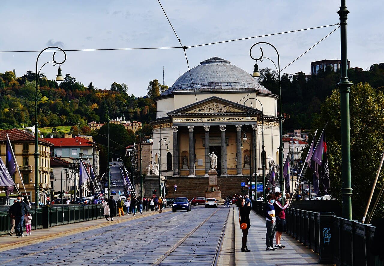 The domed church of the Gran Madre di Dio seen along the tram tracks of the bridge, the wooded hill rising behind it